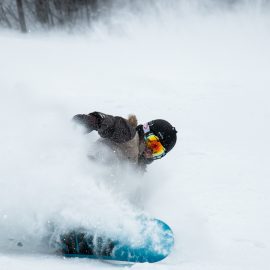 Person snowboarding spraying ice and snow into the air